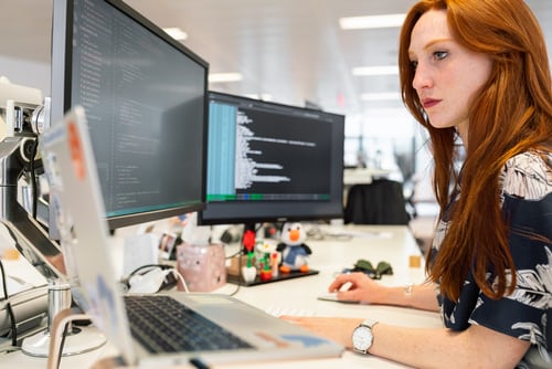 Female software engineer codes at computer